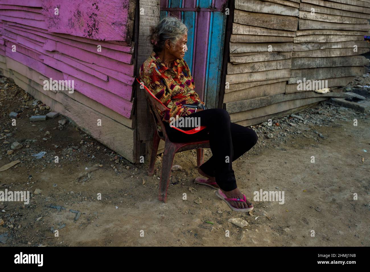 An Afro-Colombian woman sits on a chair in front of her wooden house in Olaya Herrera, a low social class neighborhood in Cartagena, Colombia. Stock Photo