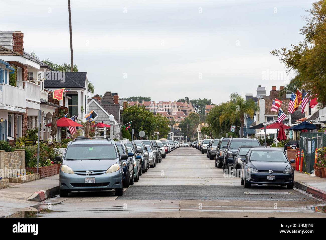 One way street on Balboa Island with parked cars and houses with American flags Stock Photo Alamy