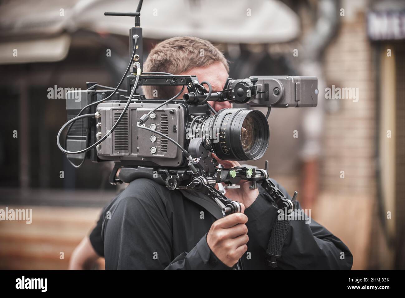 Behind the scene. Cameraman shooting the film scene with his camera on outdoor location Stock