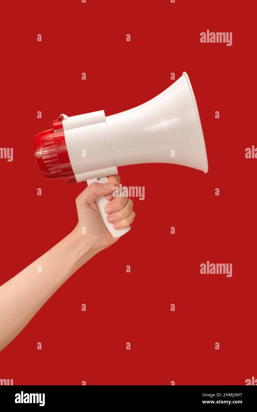 Megaphone in woman hands on a red background. Copy space. Stock Photo