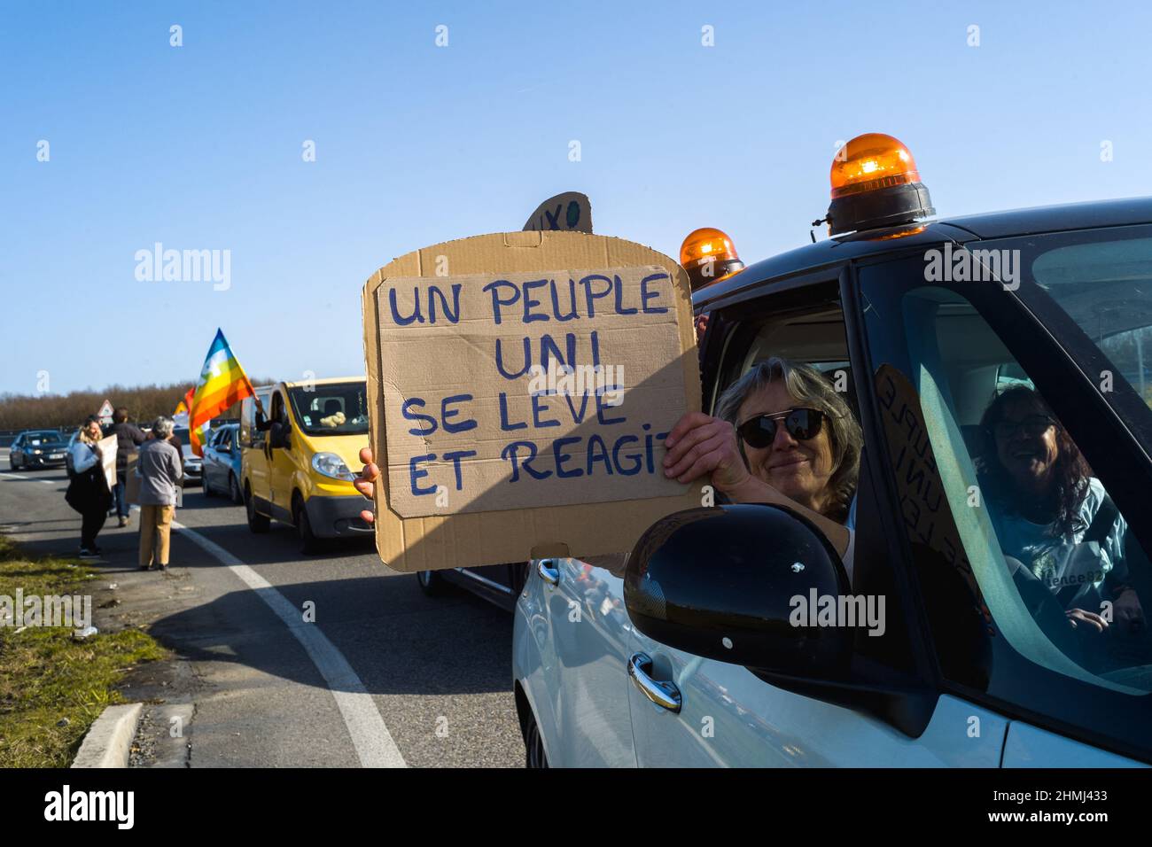 France, Montauban, 2022-02-10. A woman in a convoy car with a sign, A united people stands up and reacts. Passage of the Convoi de la Liberte at the Aussonne traffic circle in Montauban. For several days, anti health pass and anti-vax activists have been organizing road convoys to reach and blockade Paris on February 11. Movement of anger born among Canadian truck drivers against the vaccine pass. Photograph by Patricia Huchot-Boissier/ABACAPRESS.COM France, Montauban, 2022-02-10. Une femme dans une voiture du convoi avec une pancarte, Un peuple uni se leve et reagit. Passage du Convoi de la l Stock Photo