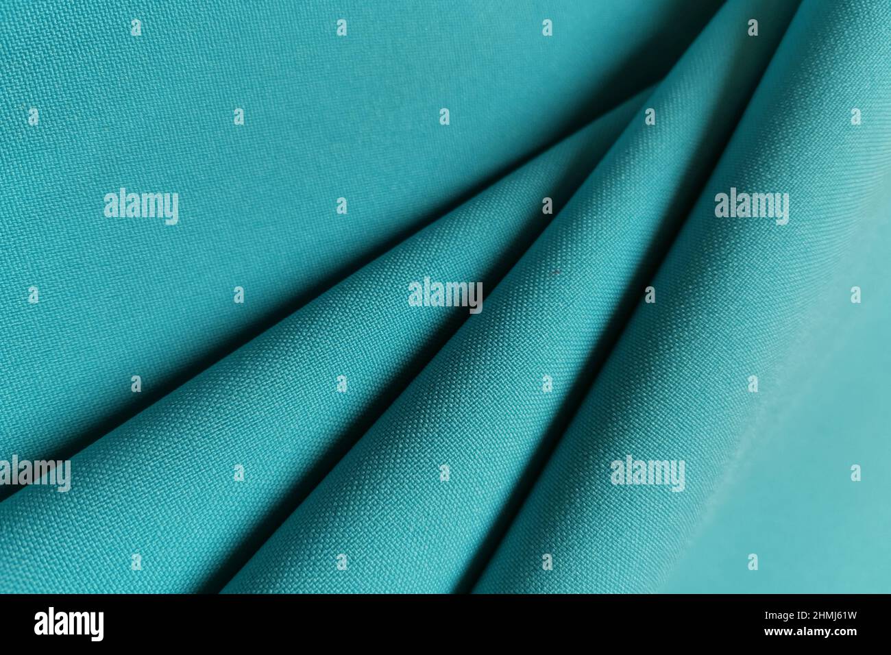Green crumpled or wavy fabric texture background. Abstract linen cloth soft waves. Gabardine wool fabric. Merino yarn. Smooth elegant luxury cloth Stock Photo
