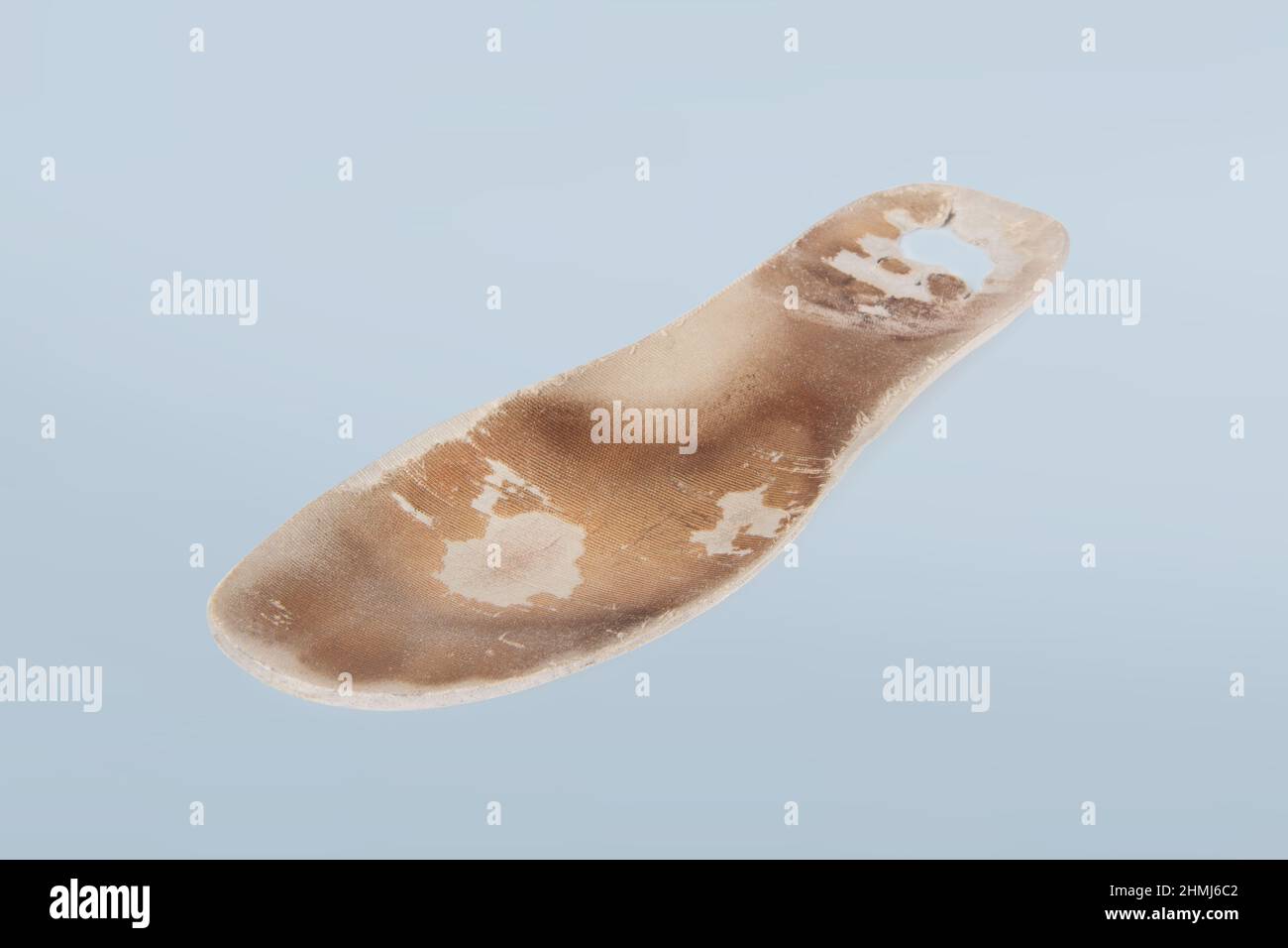 Old and shabby orthopedic insoles isolated on blue background. Dirty