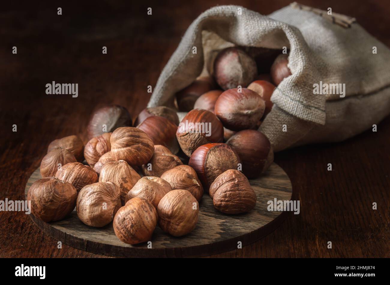 hazelnuts in a woven bag  on a dark wooden background Stock Photo