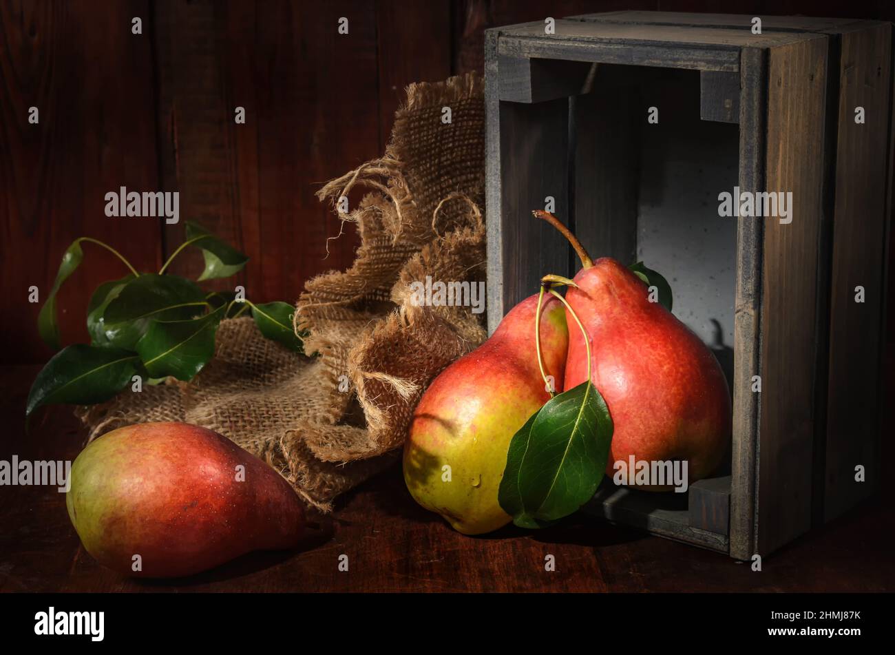 pears in bulk and a wooden box on a dark wooden background in a rustic style Stock Photo