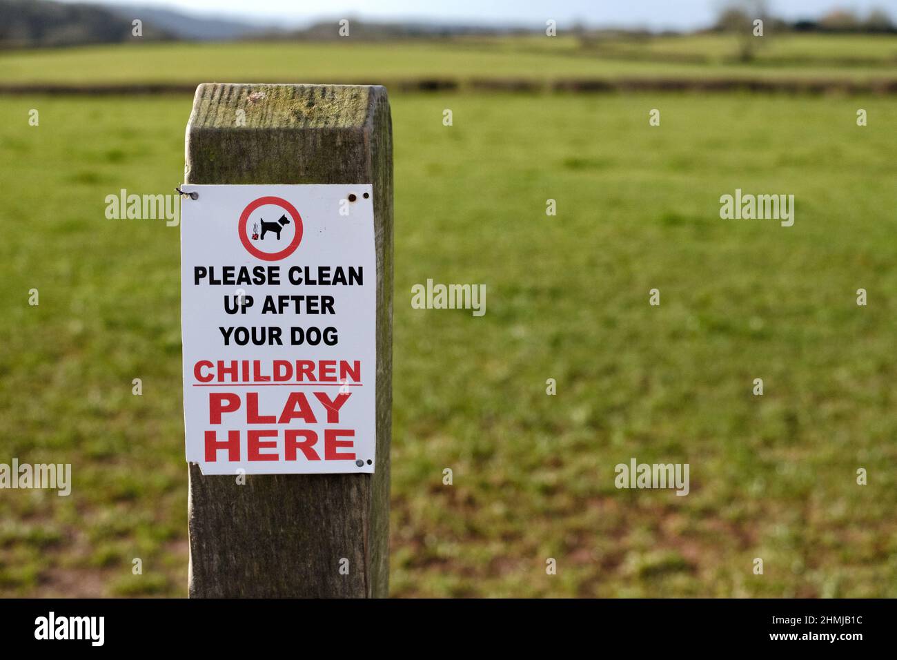 A sign fixed to a post asking dog owners and dog walkers to clear up any mess or fouling their dogs may make in an area where children play. Stock Photo