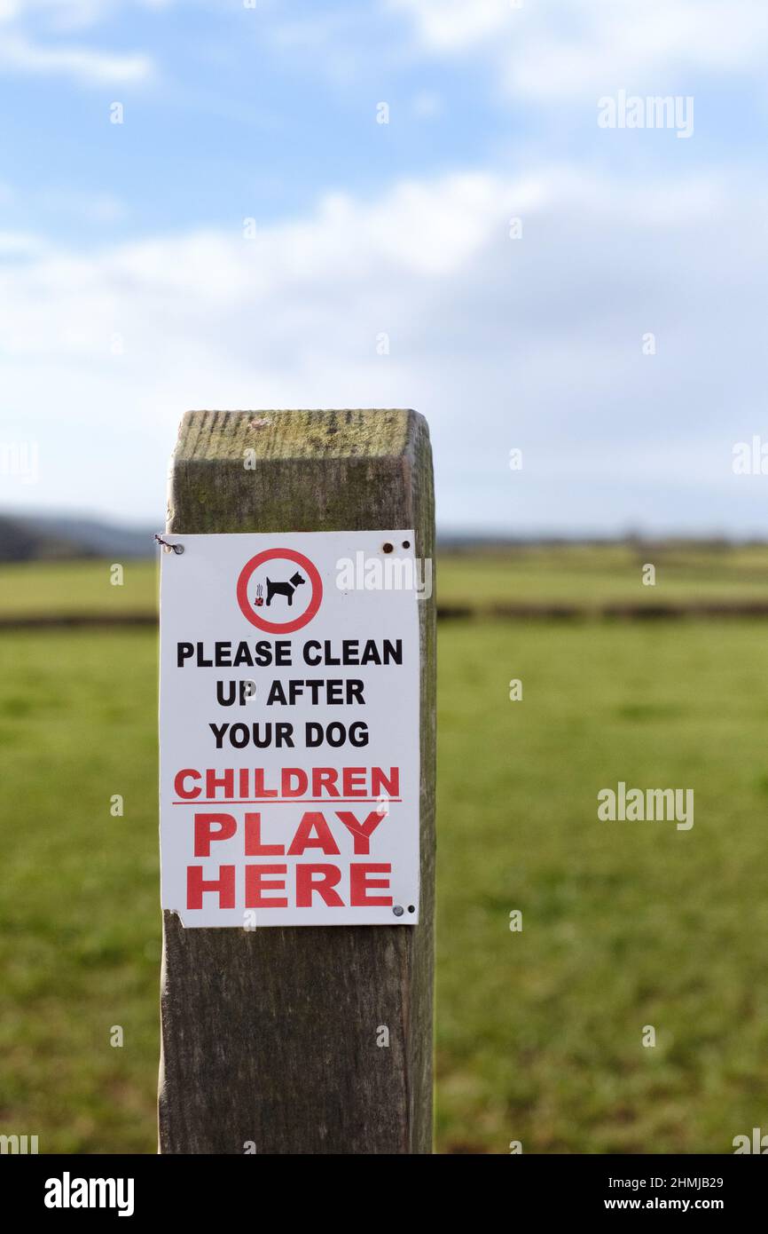 A sign fixed to a post asking dog owners and dog walkers to clear up any mess or fouling their dogs may make in an area where children play. Stock Photo