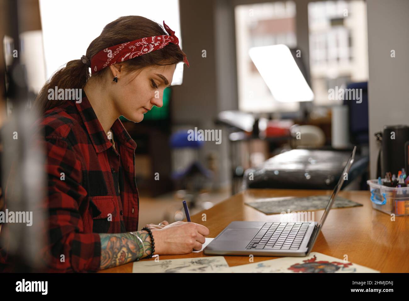 Young stylish lady tattoo master working in salon Stock Photo