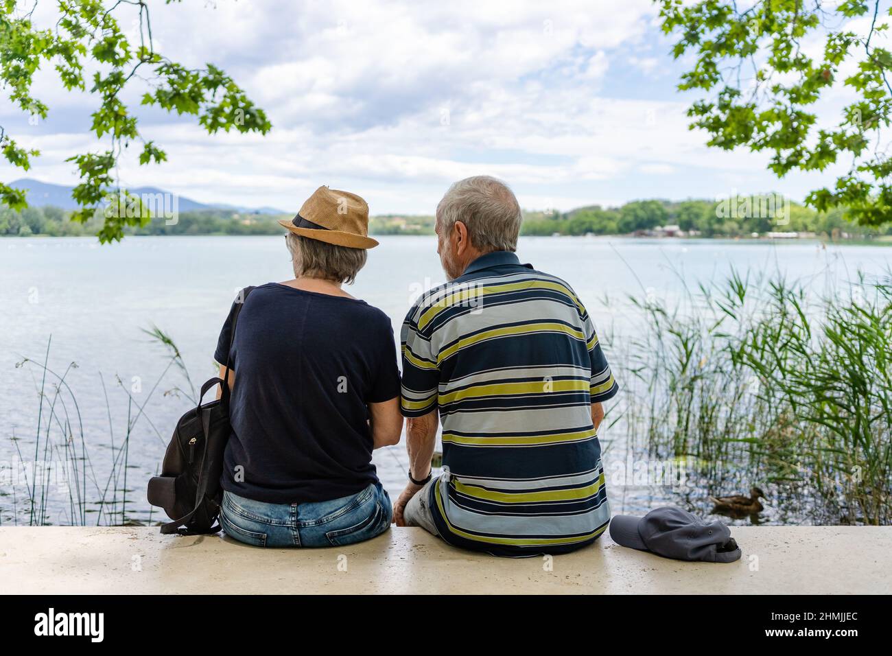 Senior couple having a rest on a bench on the waterside of Banyoles lake on a sunny day in Catalonia, Spain Stock Photo