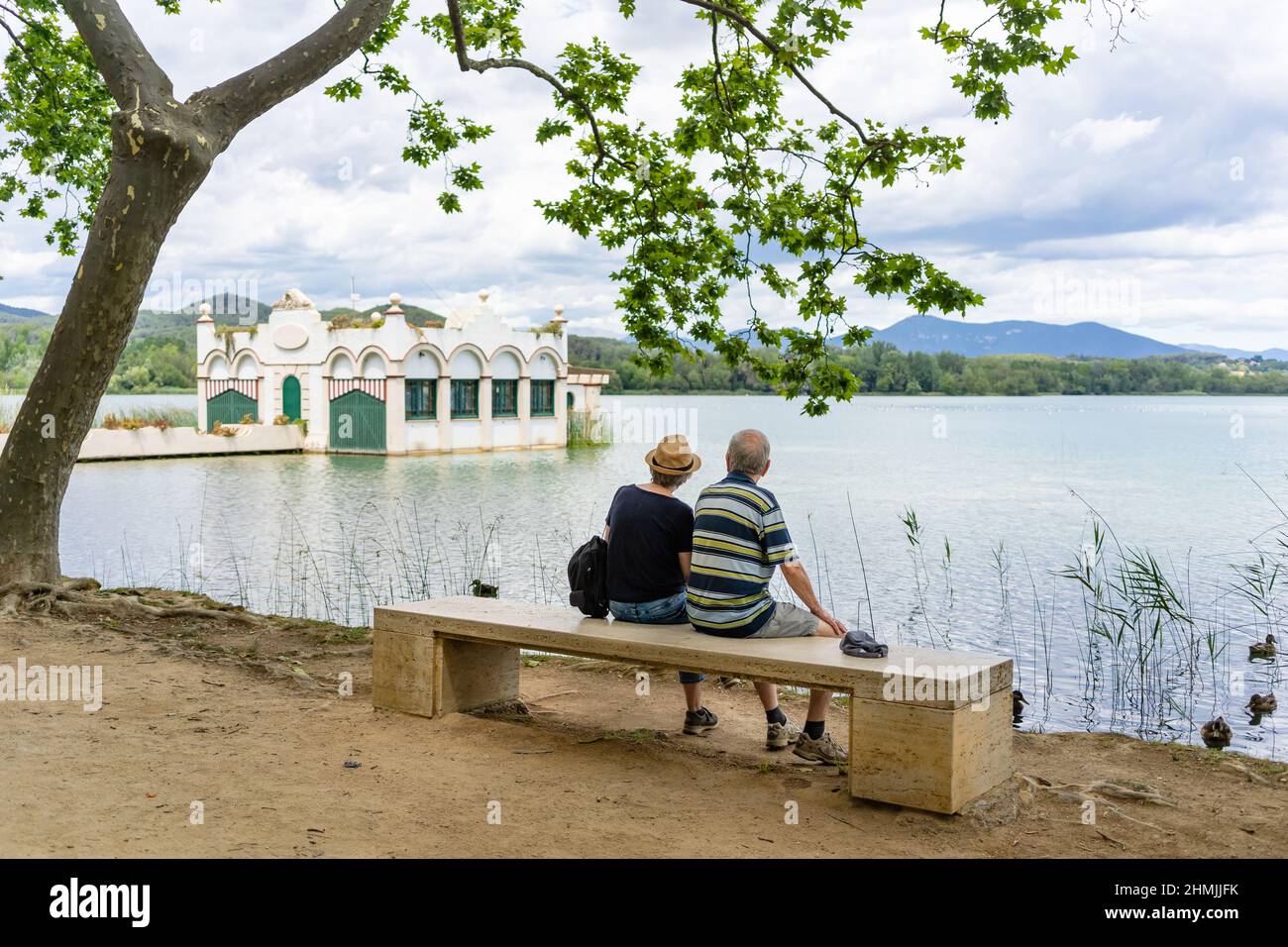 Senior couple having a rest on a bench on the waterside of Banyoles lake on a sunny day in Catalonia, Spain Stock Photo