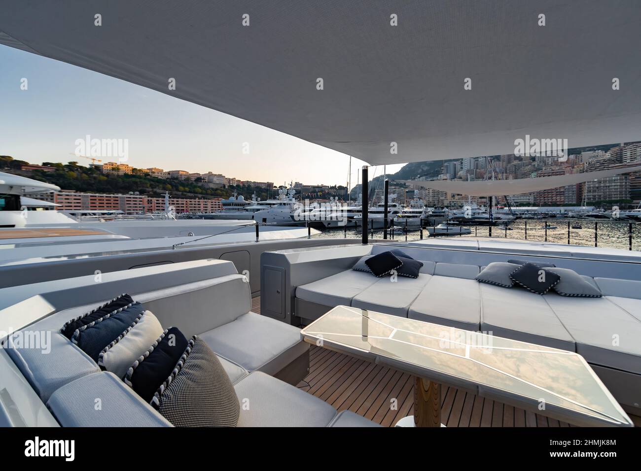 The front deck of huge yacht in port of Monaco at sunset, the place for landing of helicopter, a lot of motorboats are on background, the chrome Stock Photo