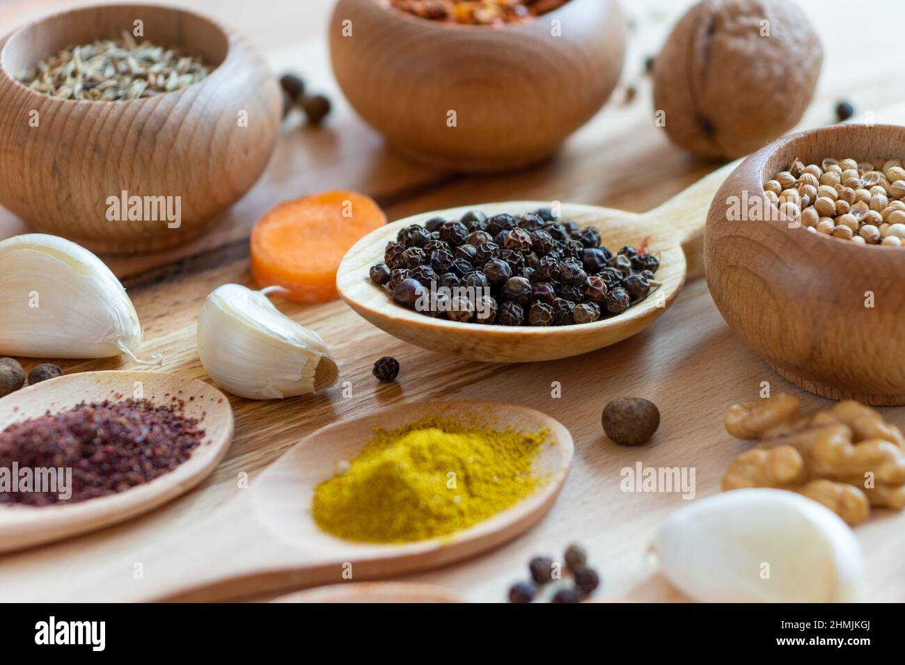 Different spices arranged in wooden spoons and bowls over wooden board Stock Photo