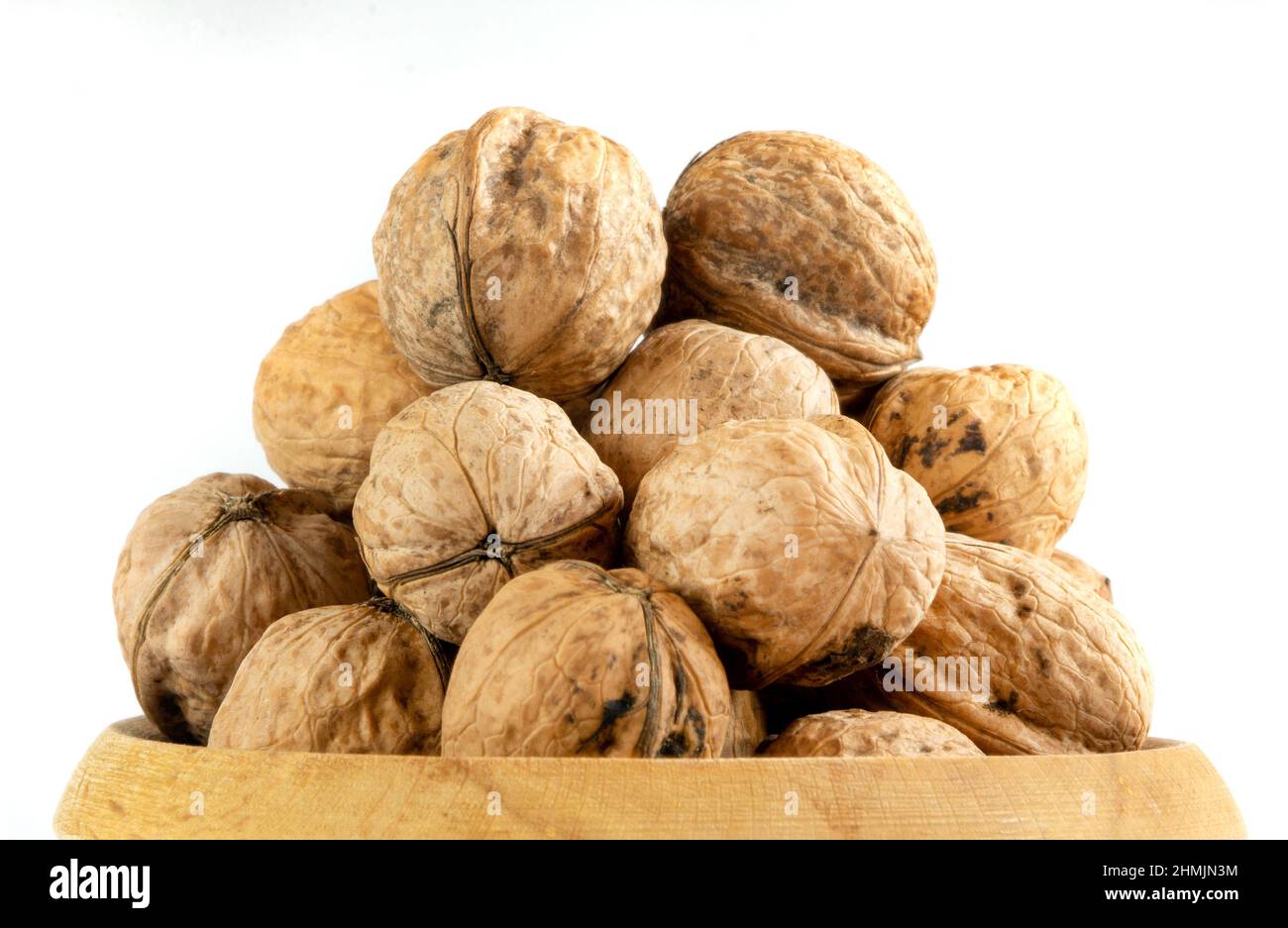 Whole solid walnuts in wooden bowl on white background Stock Photo