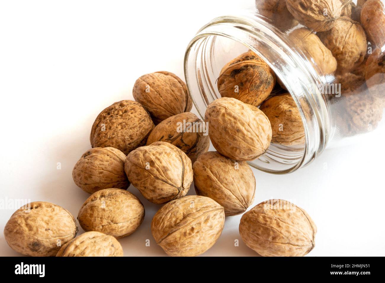 Whole solid walnuts in a jar on white background Stock Photo
