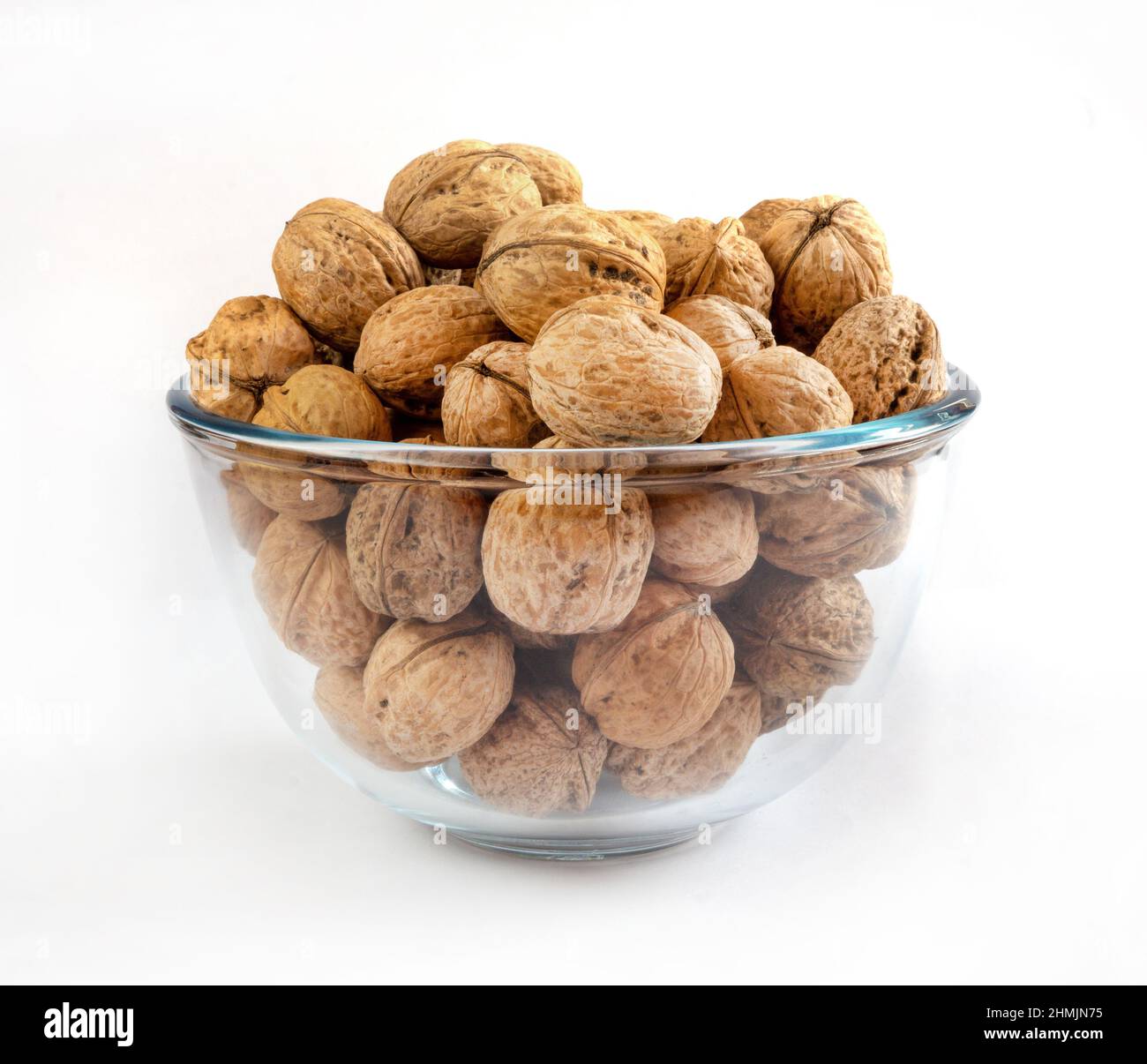 Whole solid walnuts in a glass bowl on white background Stock Photo
