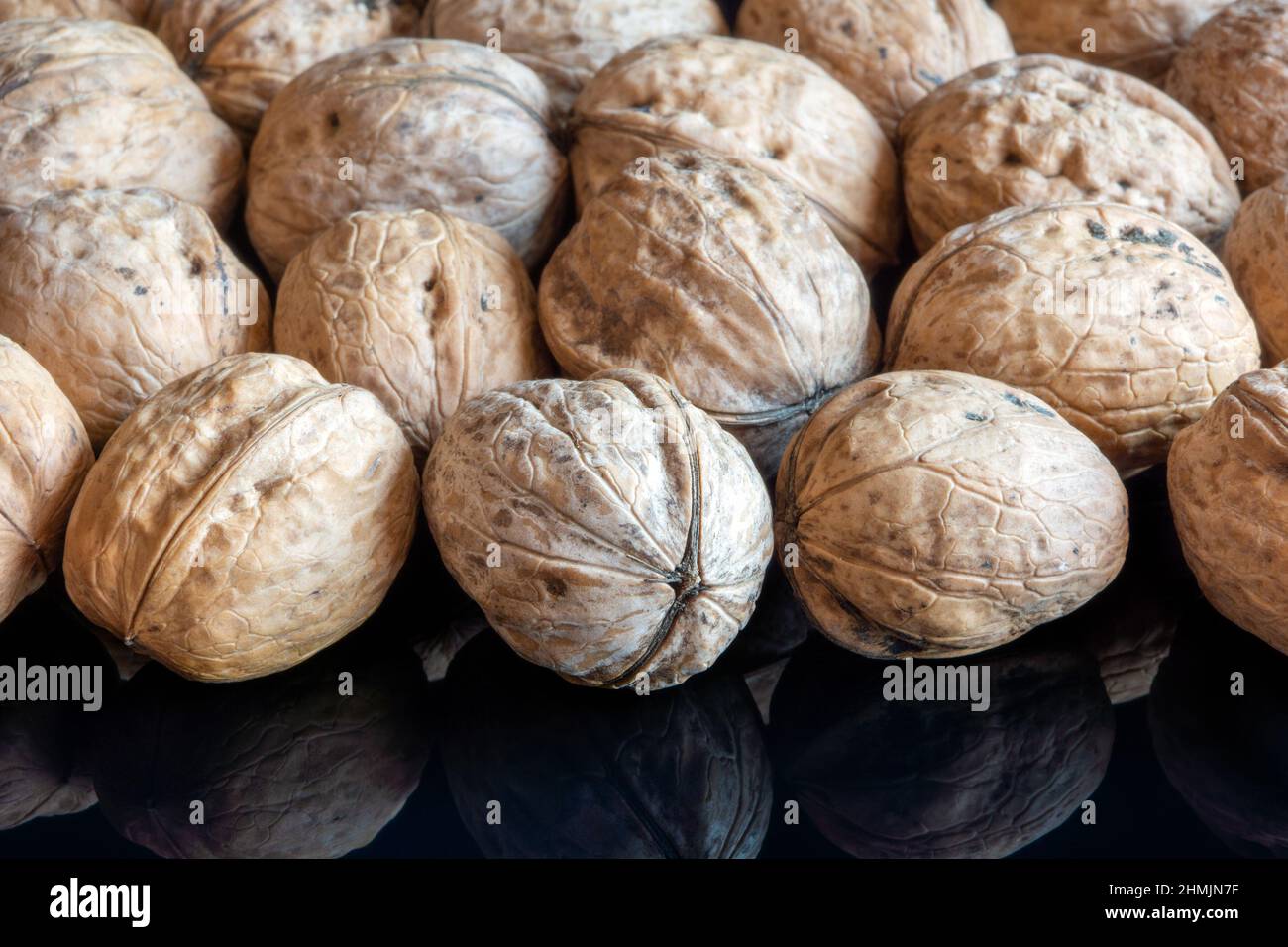 Whole solid walnuts on black reflective background Stock Photo