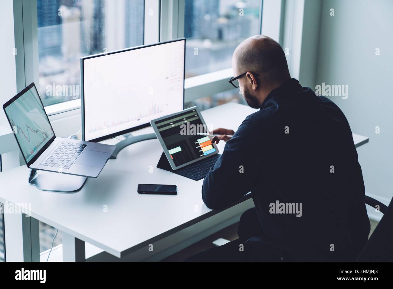 Anonymous trader analyzing data on tablet and computers in office Stock Photo