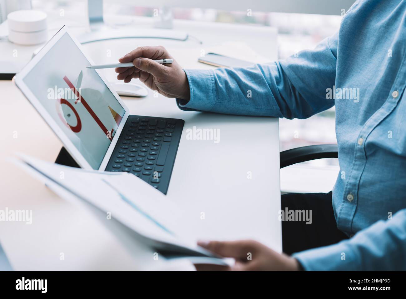 Crop man using stylus while working on tablet and analyzing documents Stock Photo