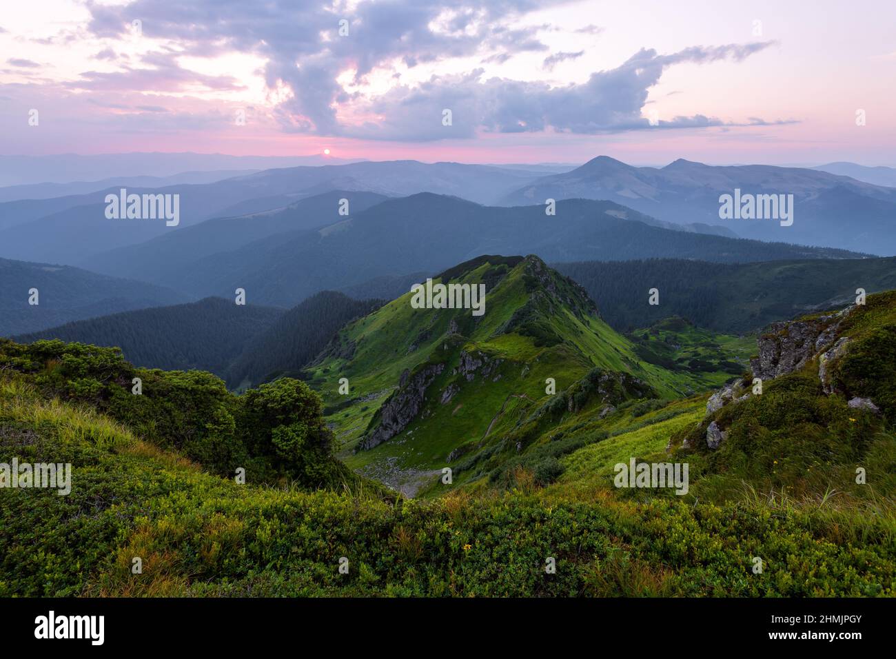 Mountain landscape with beautiful sunrise, cloudy sky and pink colorful horizon. Spring sunny morning. Wallpaper background. Location place Maramures, Stock Photo
