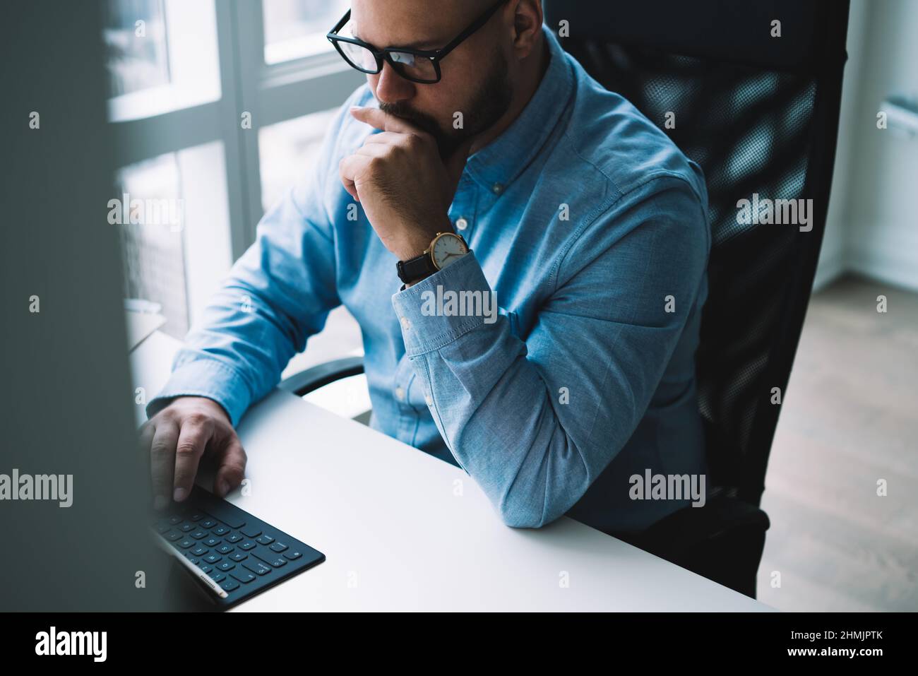 Focused young man working on netbook in light stylish office Stock Photo