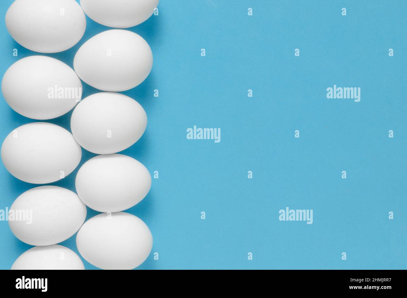 White chicken eggs on blue background.Close up Stock Photo