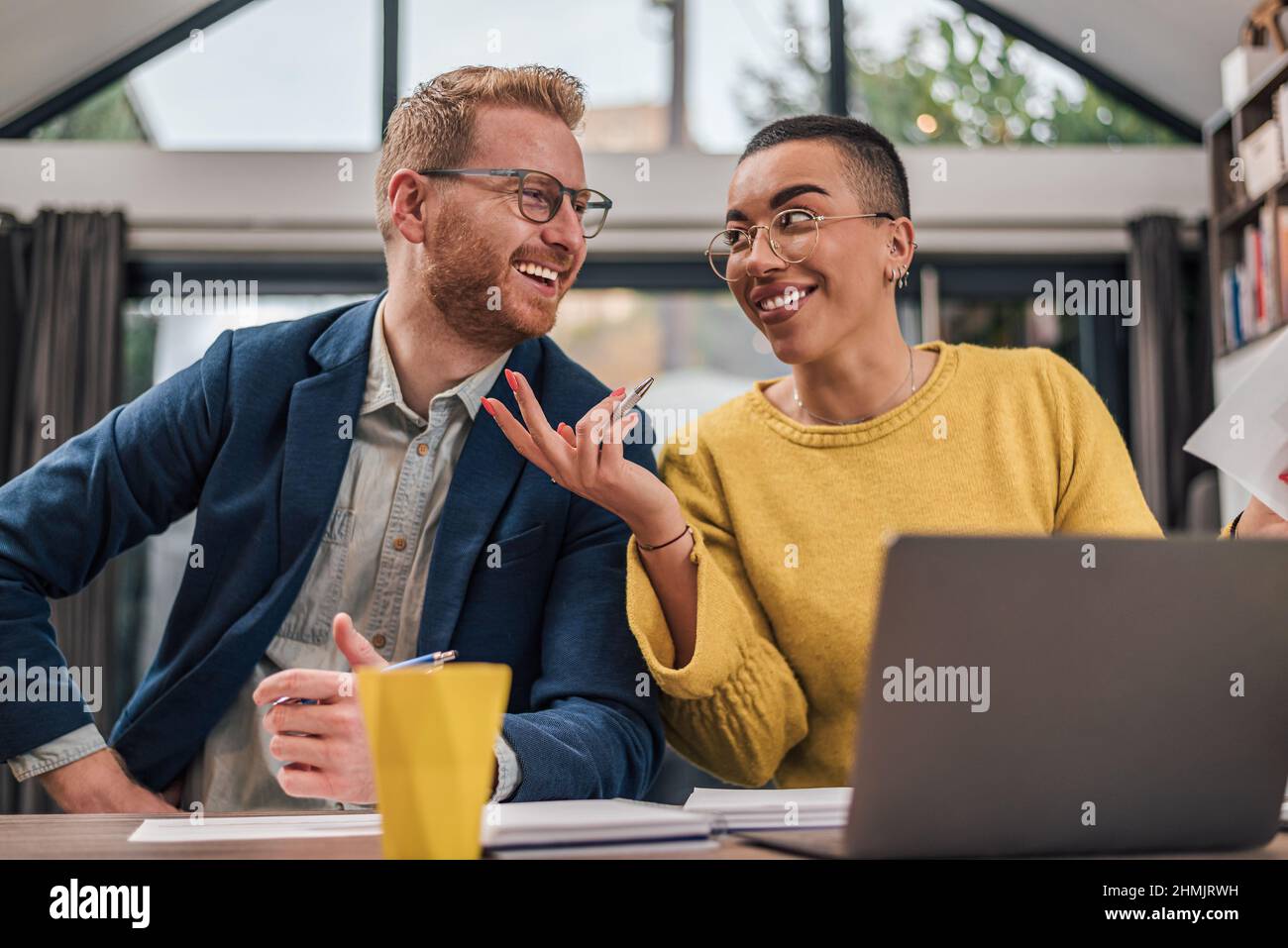 Smiling happy laughing cheerful satisfied couple of diverse businesspeople doing paperwork together and a new small business start planing while worki Stock Photo