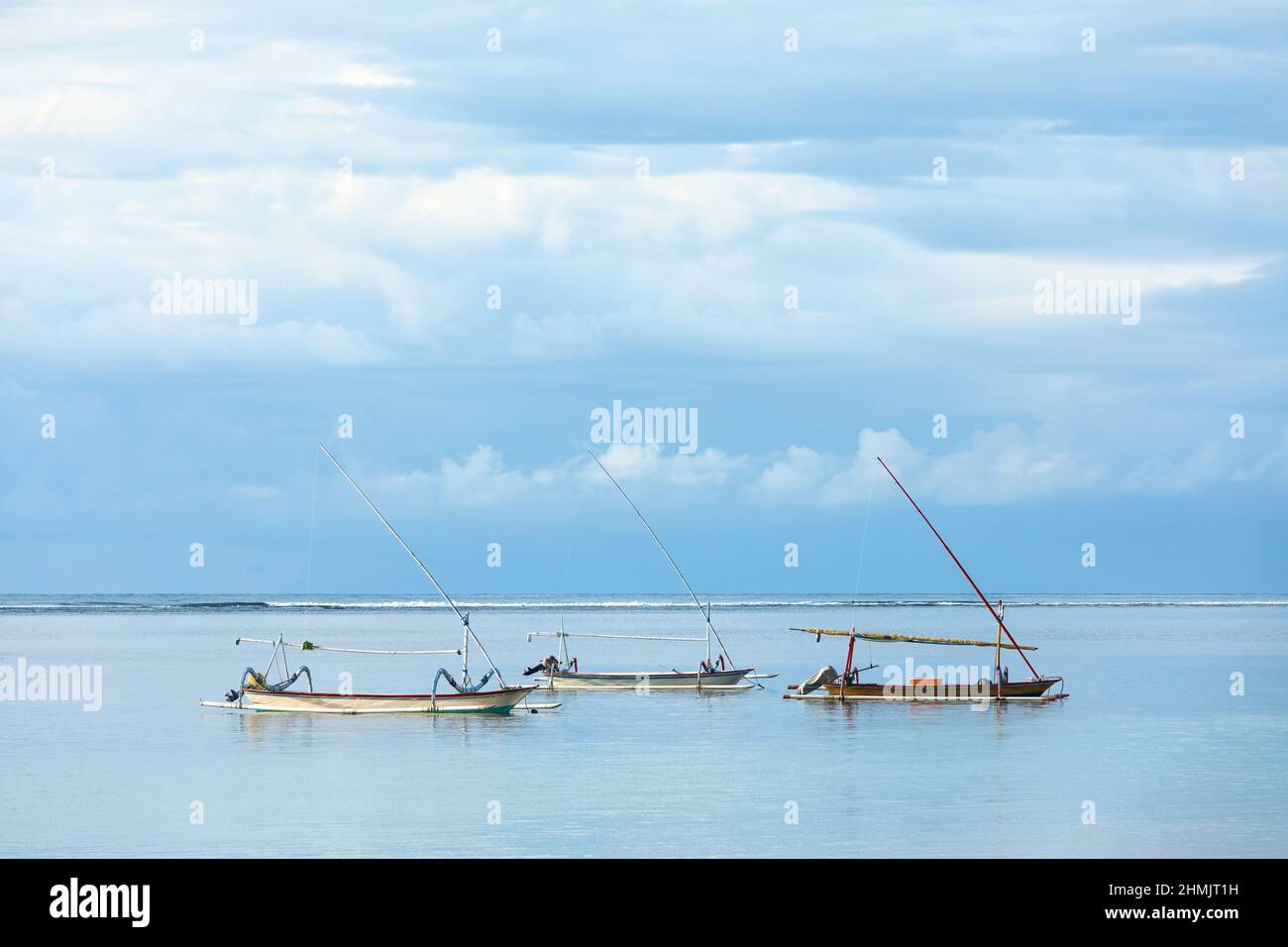 Traditional fishing boats called jukung on the white sand beach. Nusa dua beach, Bali island, Indonesia. High waves with foam spread on the coast. Ama Stock Photo