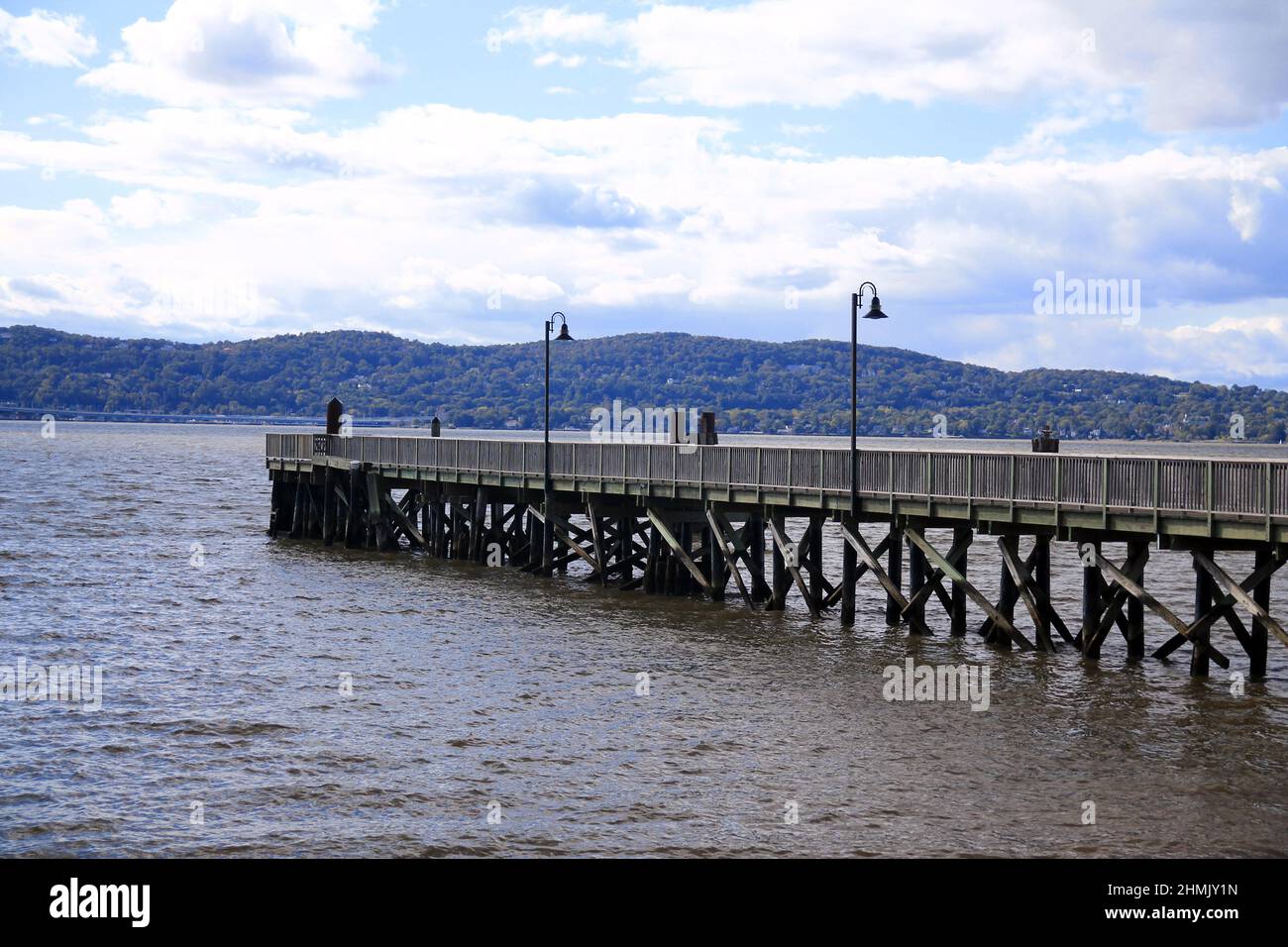 The wooden pier with the black lamps on the brown Hudson river Stock Photo