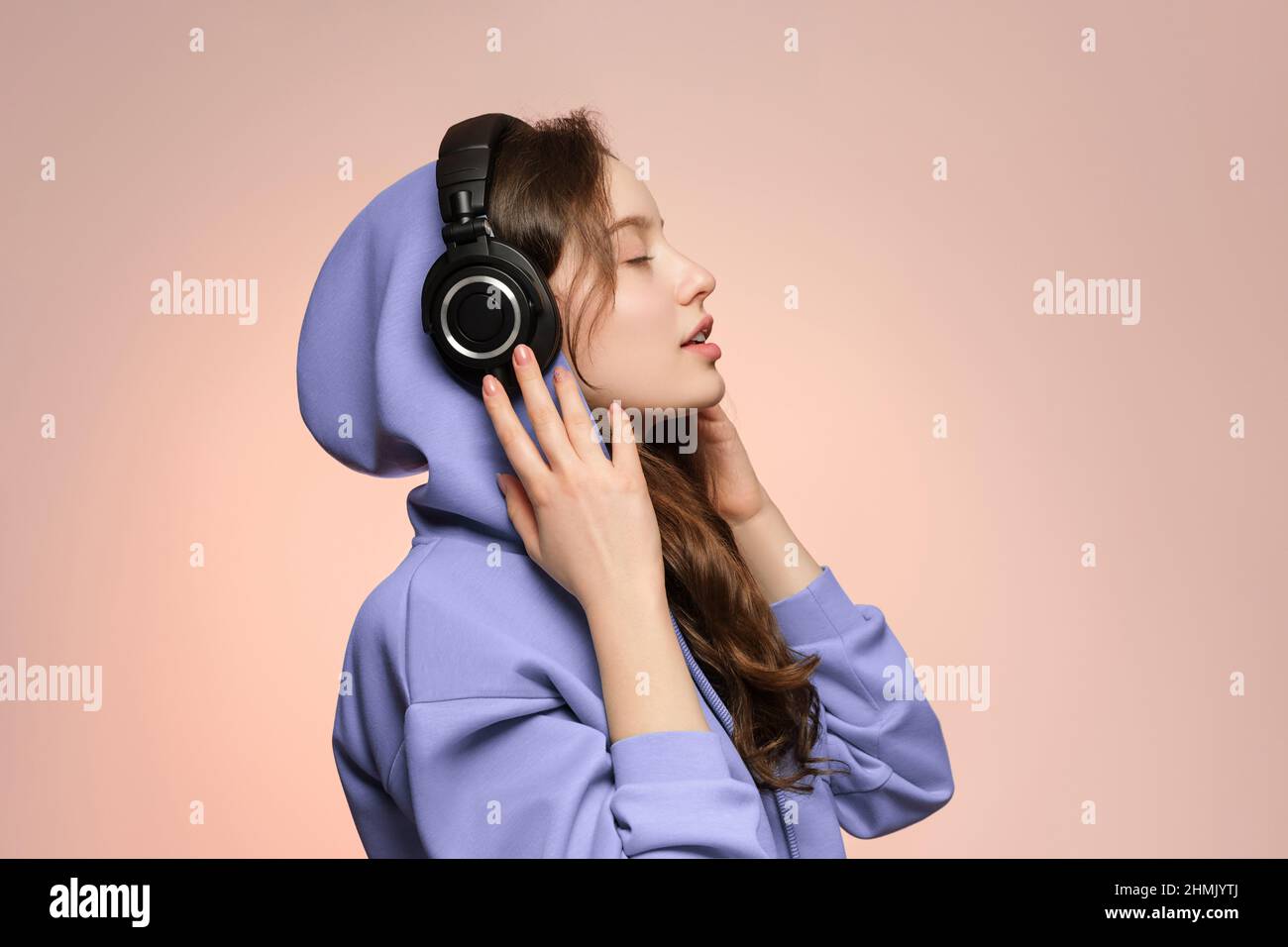 Girl in wireless headphones, face in profile on a soft pink background