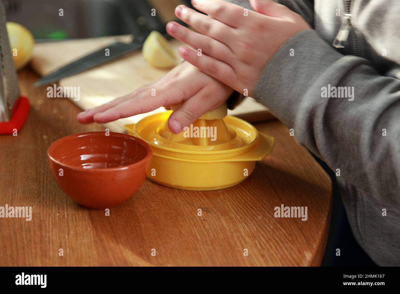 Close-uo of hands squeezing a lemon using a manual squeezer. Stock Photo