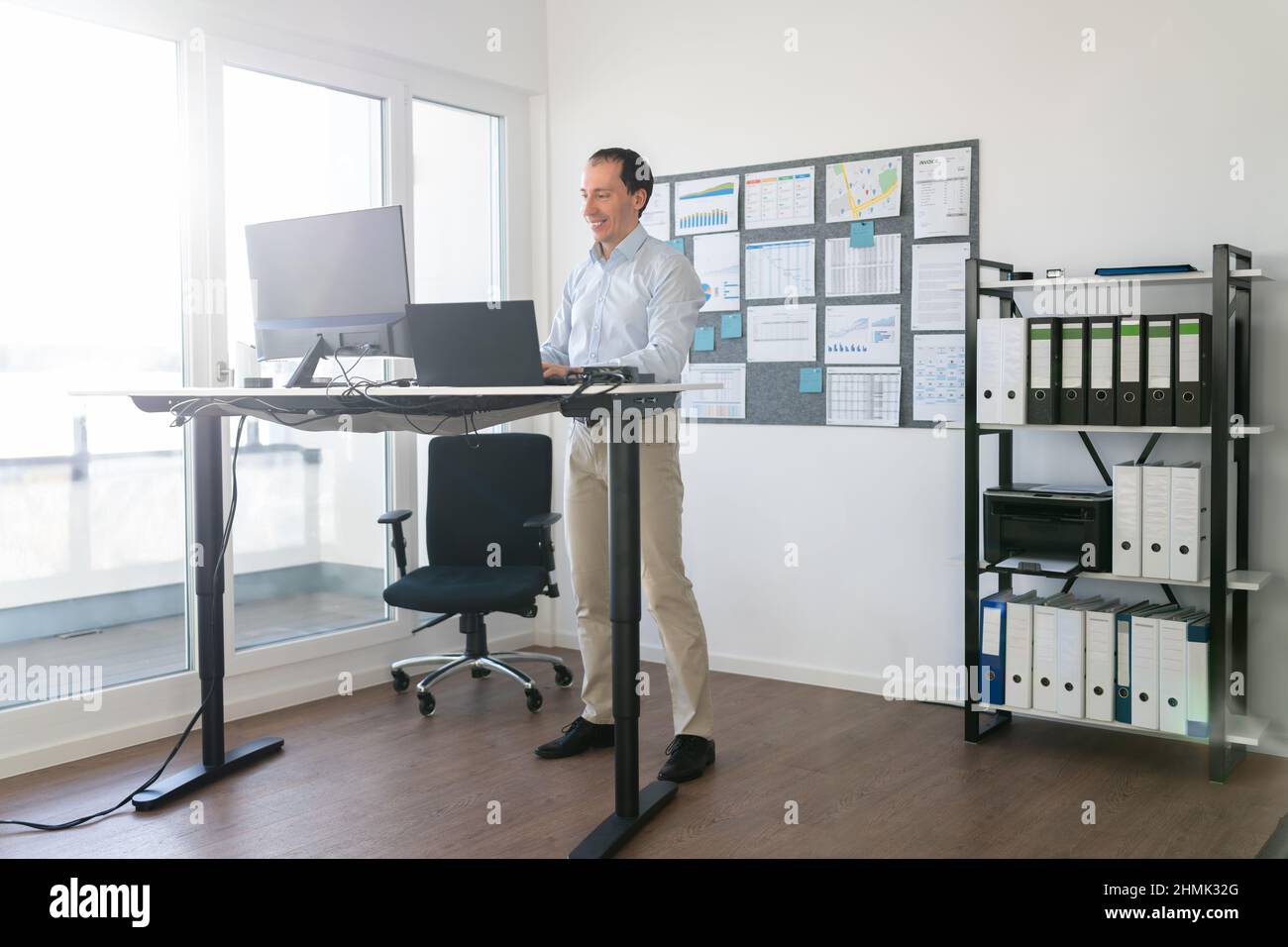 Man Using Adjustable Height Standing Desk In Office For Good Posture