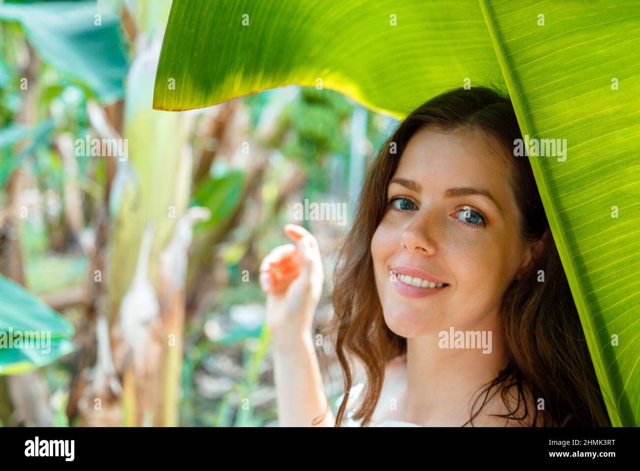 Beautiful young caucasian brunette woman portrait near banana palm leaves tropical plants in jungle. Skin care and natural organic beauty, personal Stock Photo