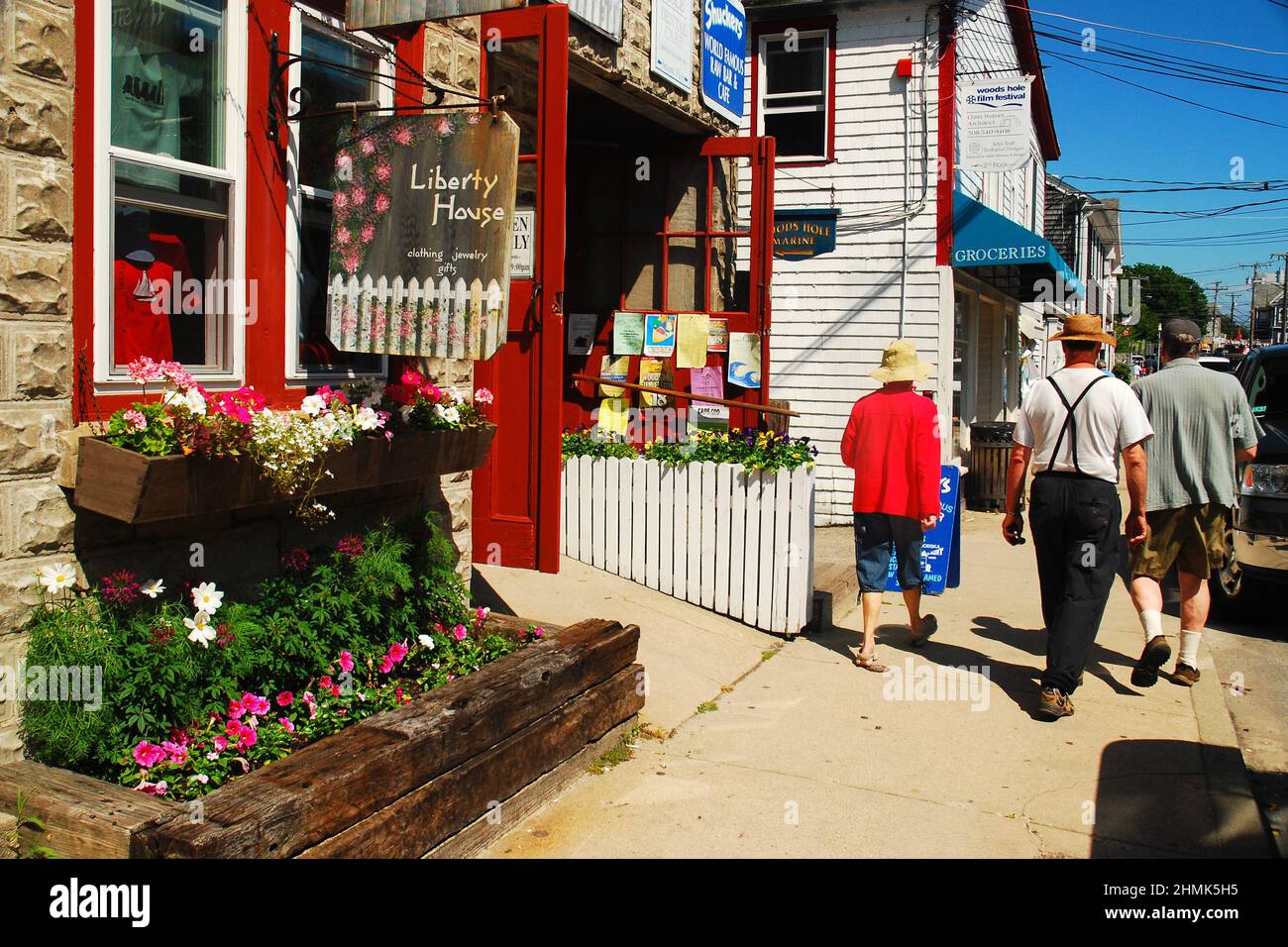 A group of friends walk through the charming downtown district of Woods Hole on Cape Cod Massachusetts during a sunny summer day Stock Photo