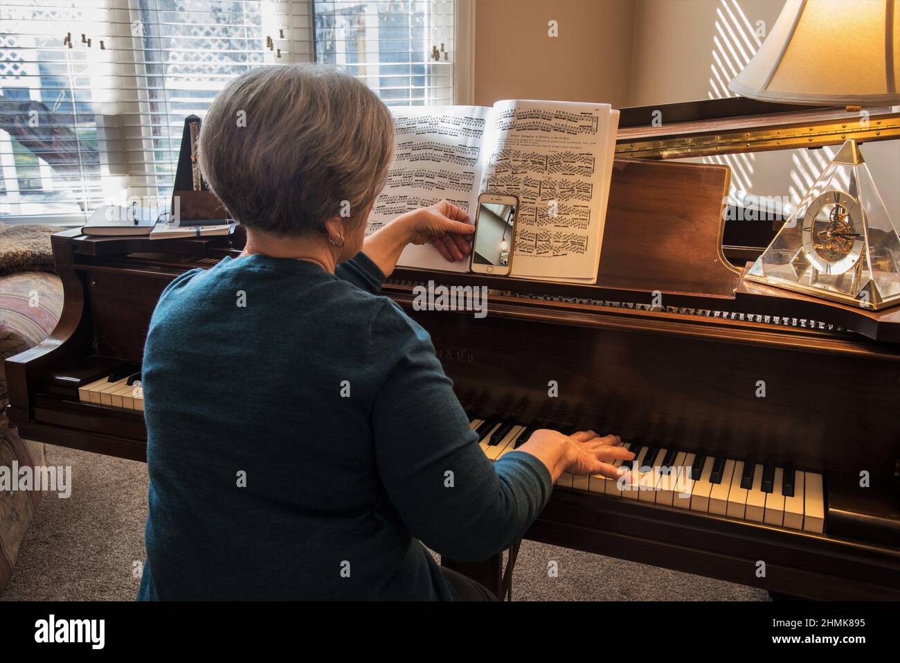 South Jordan, Utah, USA. Feb. 10, 2022. A piano teacher uses a smart phone and facetime to teach a virtual piano lesson. A difficult process. Stock Photo