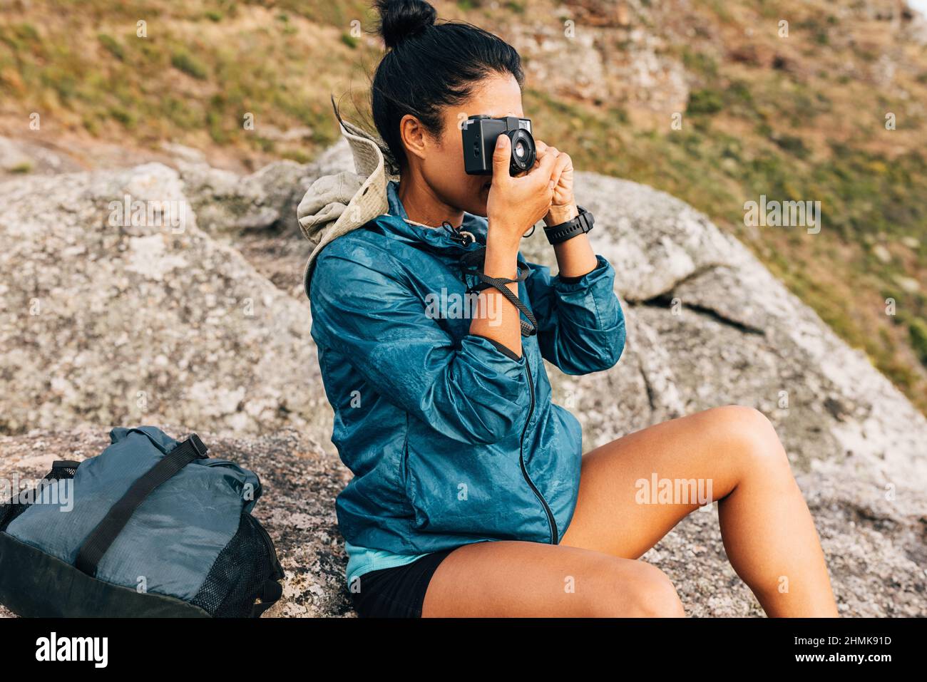 Woman tourist taking photographs on a film camera sitting on a rock Stock Photo