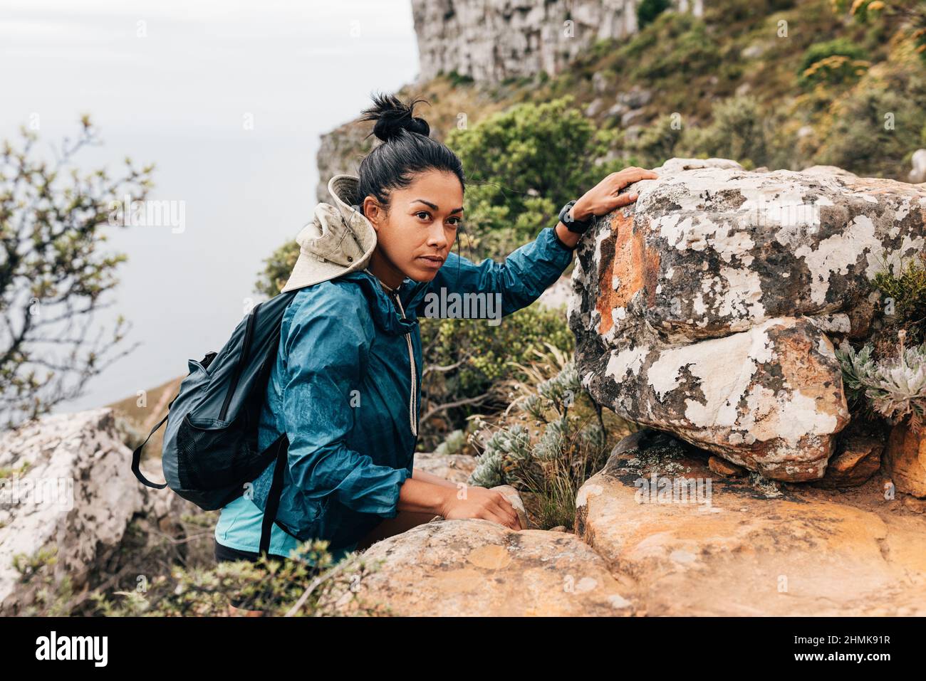 Portrait of woman hiker climbing rock and looking away. Young female ...