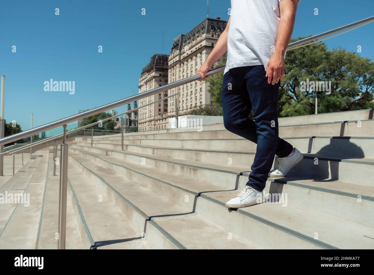 An unrecognizable latino man with a jean and white sneakers going down a cement stairs. Horizontal orientation. Stock Photo