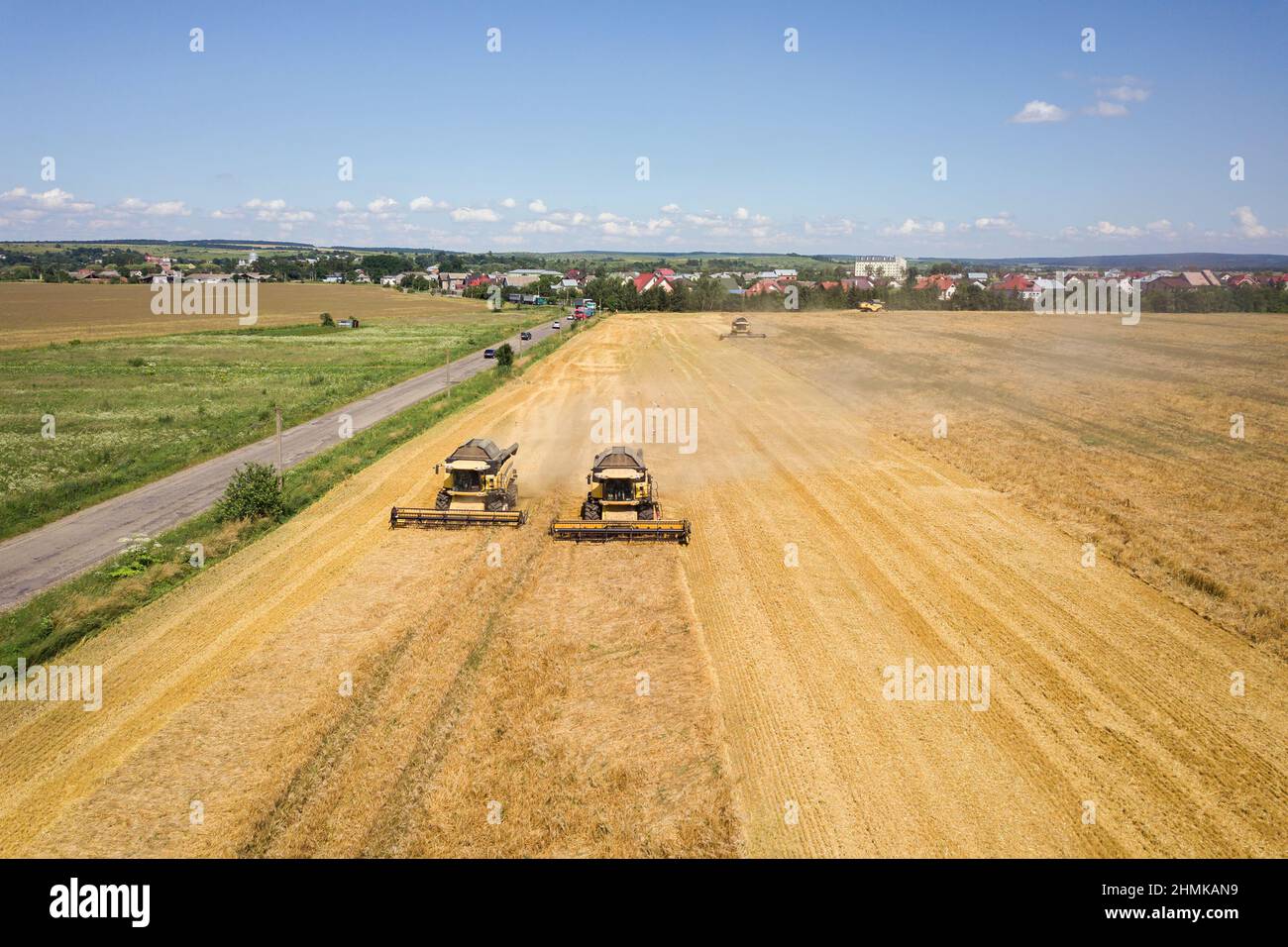 Aerial view of combine harvesters harvesting large yellow ripe wheat ...