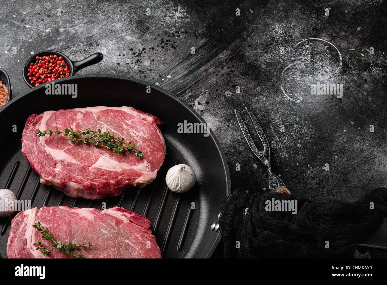 Fresh raw Rib eye Steak with seasonings set, on black dark stone table