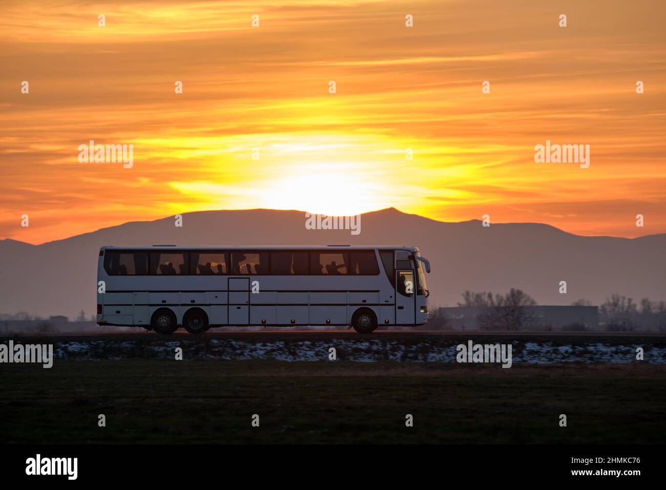 Intercity passenger bus driving on highway road in evening Stock Photo