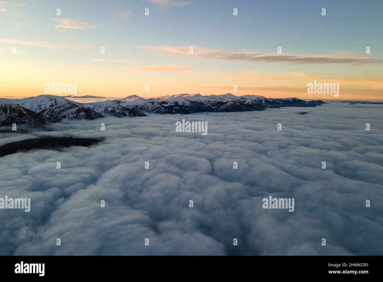 Aerial view of vibrant sunrise over white dense clouds with distant ...