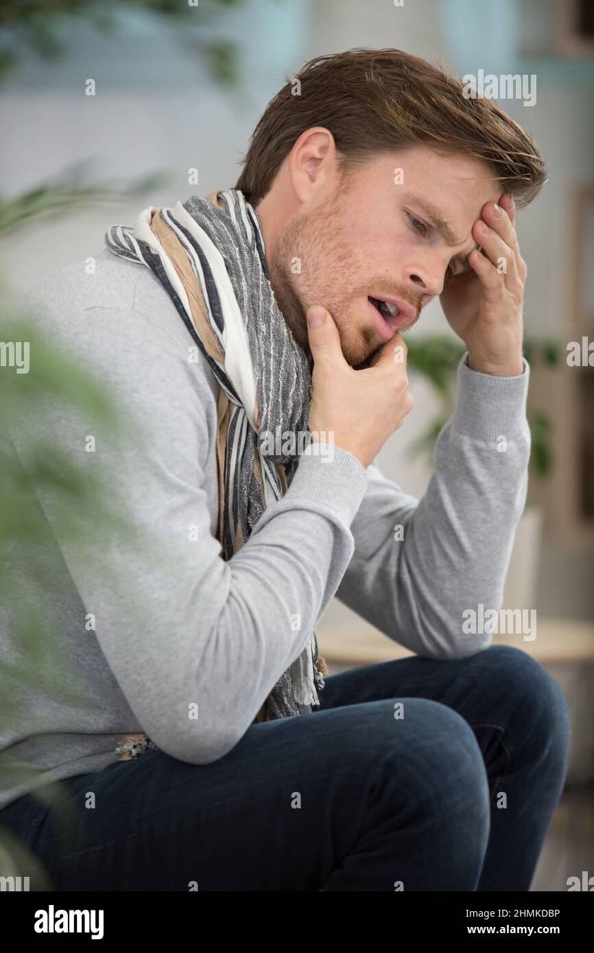 man sitting on sofa suffering from toothache Stock Photo - Alamy