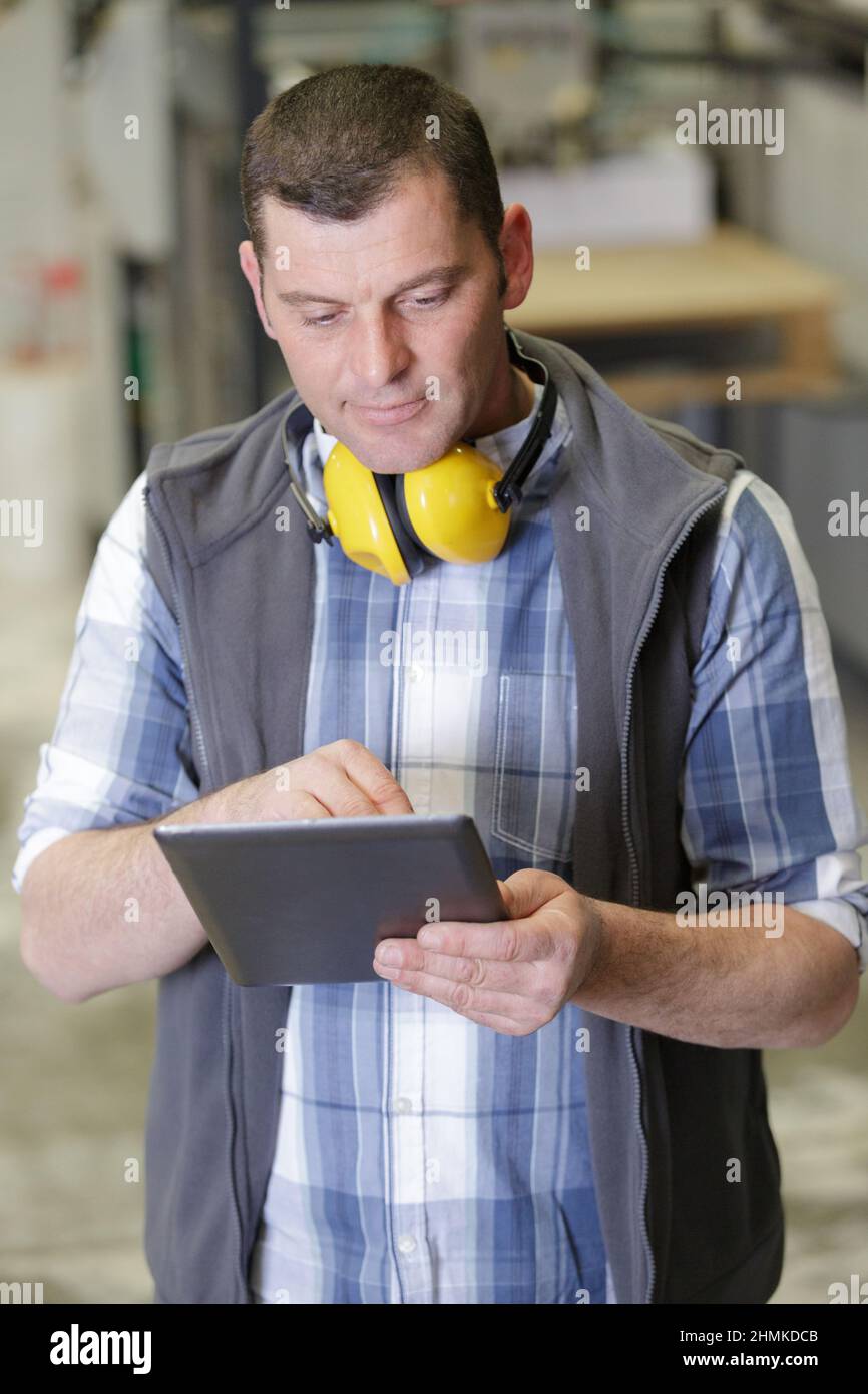 middle aged male worker using tablet in a factory Stock Photo