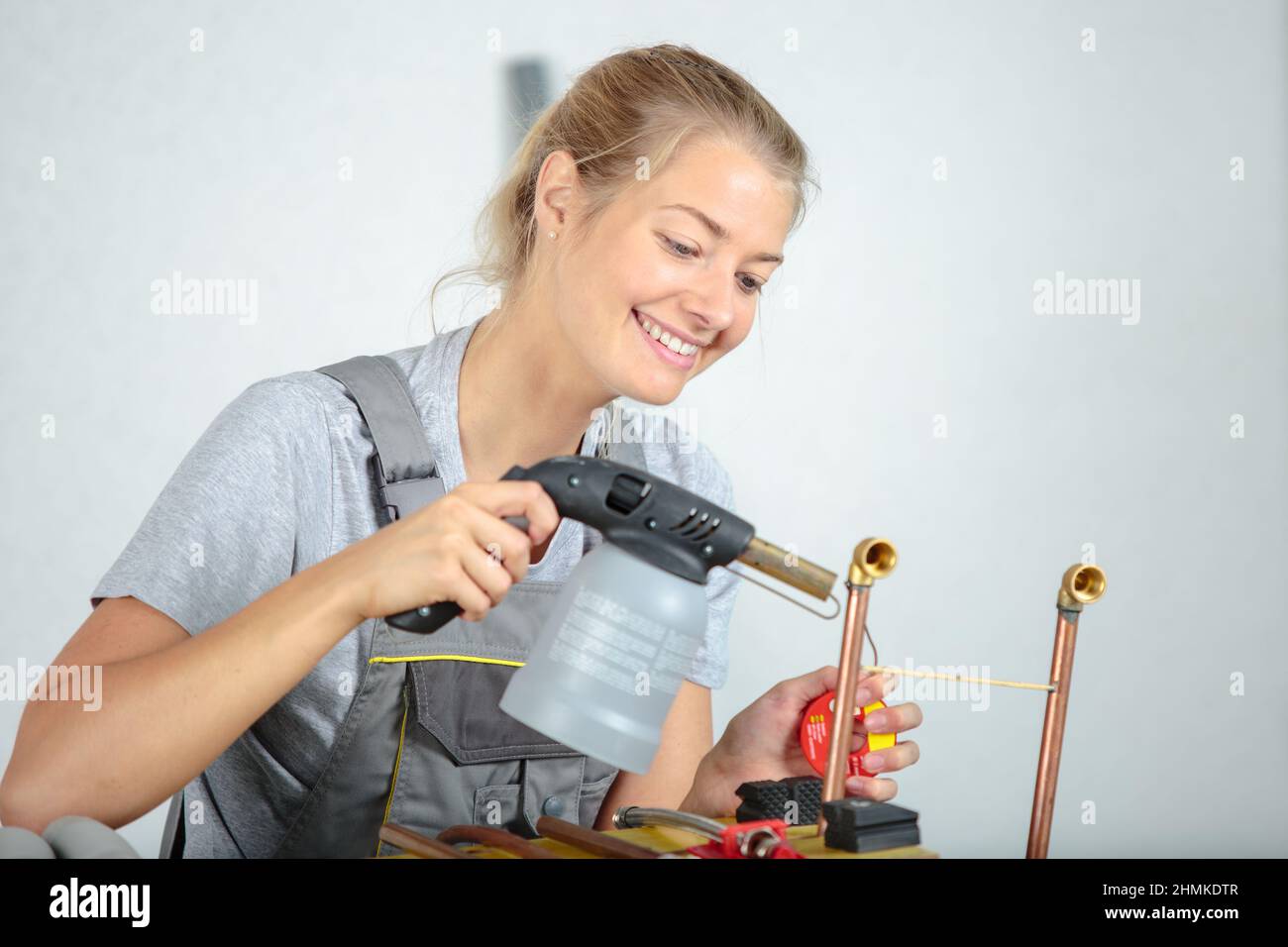 happy female worker using blowtorch on copper pipe Stock Photo Alamy