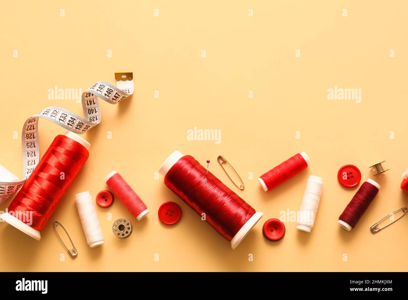 Thread spools, buttons and measuring tape on color background Stock Photo