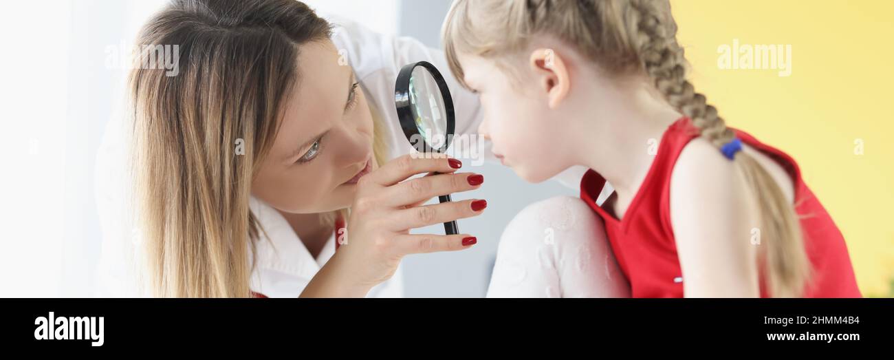 Ophthalmologist conducts medical examination of girl eye through magnifying glass Stock Photo
