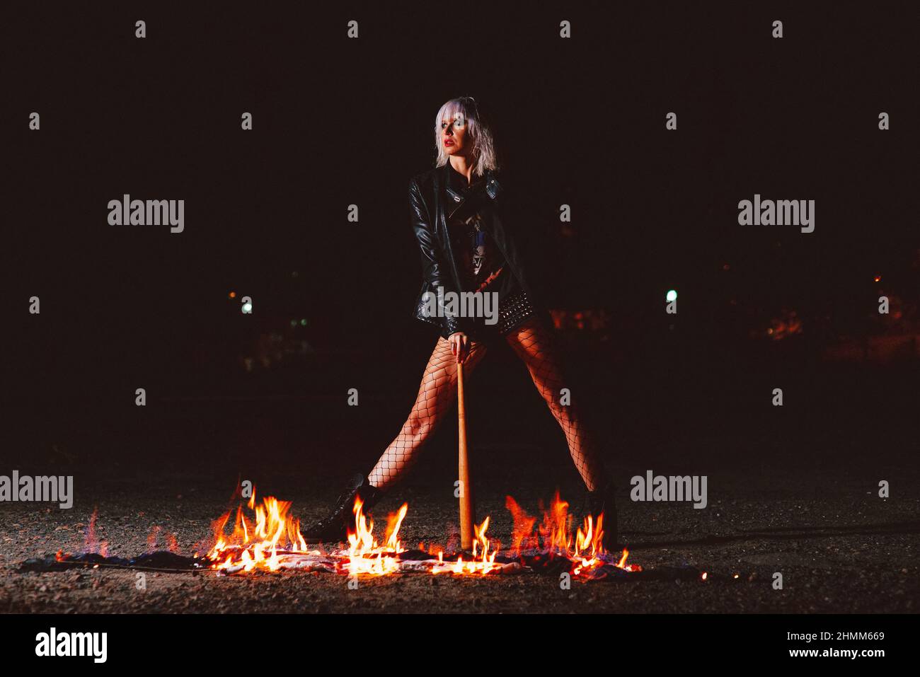 Portrait of stylish blonde grunge young woman  with the club near the fire Stock Photo