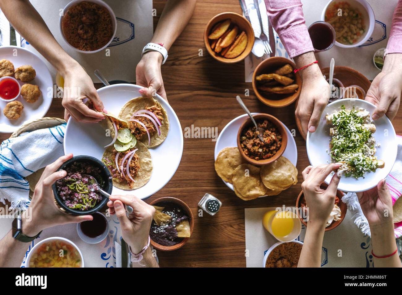 group of latin Friends eating Mexican Tacos and traditional food, snacks and peoples hands over table, top view. Mexican cuisine Latin America Stock Photo
