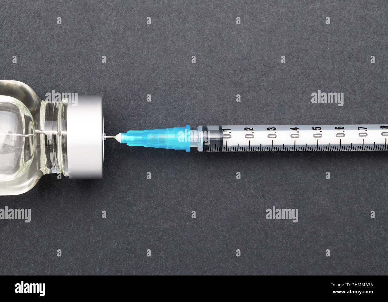 Liquid medicine in vials and injection syringe on dark gray background Stock Photo
