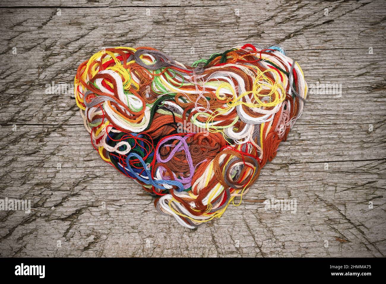 Heart shaped entangled thread on grungy wooden background Stock Photo